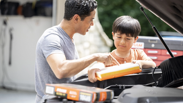 A man teaches his son on the simple installation process of a FRAM engine air filter, which is specifically engineered to fit on a wide range of vehicles.