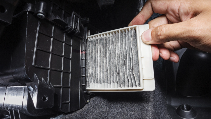 A DIYer is replacing the old cabin air filter with a new FRAM filter, designed to fit a wide range of vehicle models.